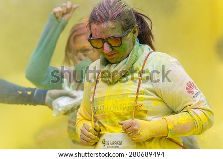 STOCKHOLM, SWEDEN - MAY 23: Happy woman in yellow and sunglasses running at Stockholm Color Run in Tantolunden or Tanto on May 23, 2015. People from all walks of life participated in the run.