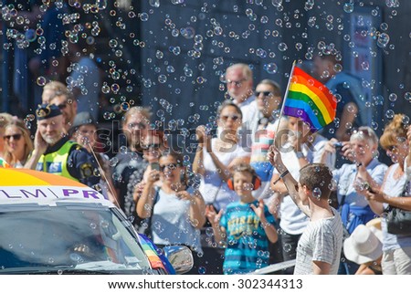 STOCKHOLM, SWEDEN - AUGUST 1, 2015: Man with rainbow flag and bubbles during the Pride parade in Stockholm