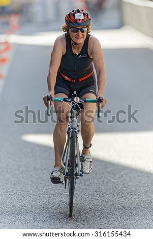 STOCKHOLM - AUG 23, 2015: Older woman triathlete on a bike in the old town in the ITU World Triathlon event in Stockholm.