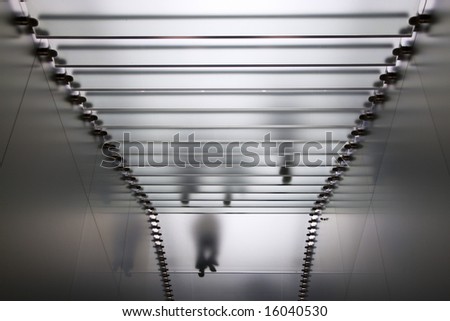 Silhouette of people walking down translucent glass steps inside a high tech building