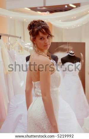 Pretty young bride-to-be at the bridal shop posing in a bridal gown.