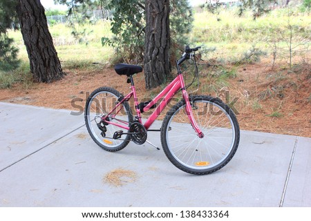 Woman\'s pink bicycle parked on foot path bike track in country setting