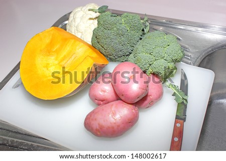 Vegetables being prepared on chopping board on kitchen sink