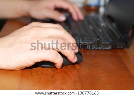 Close-up of man hand on mouse while working on laptop