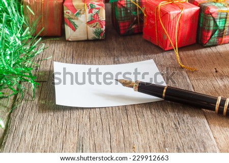 Christmas gift boxes and fountain pen over wooden background