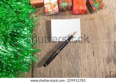 Christmas gift boxes and fountain pen over wooden background