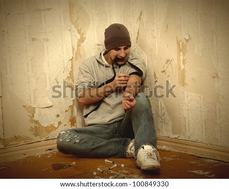 bad guy - addict  with a syringe using drugs  sitting on the floor