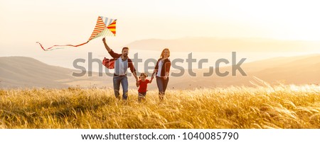 Photo of Happy family father,  mother and child daughter launch a kite on nature at sunset