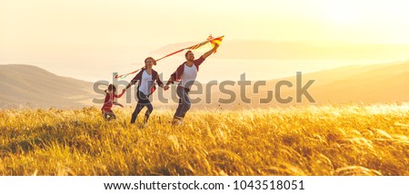 Happy family father,  mother and child daughter launch a kite on nature at sunset 商業照片 © 