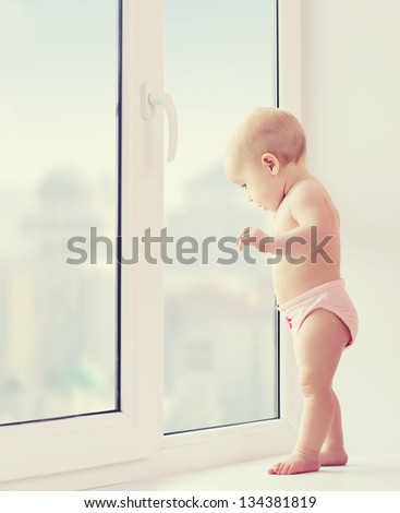 A baby girl looking out the window longing, sadness, and waiting