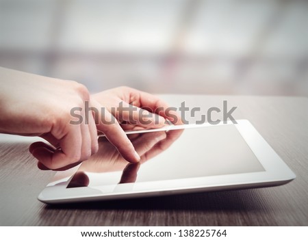 white tablet with a  blank screen in the hands on wooden table