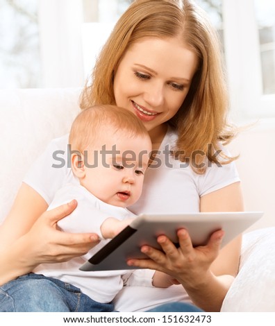 mother and baby are looking to play and read tablet computer on the couch at home