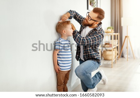 concept of development, growing up. a father measures height of his young child son