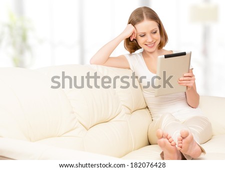happy woman with tablet pc  on the sofa at home