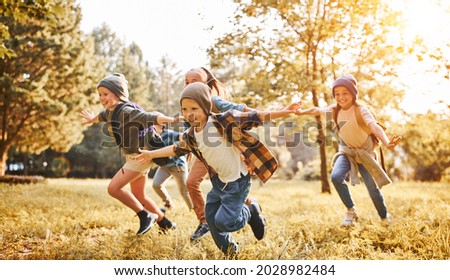 Group of happy joyful school kids with backpacks running with outstretched arms in forest on sunny spring day, excited children scouts boys and girls having fun during camping activity in nature Foto stock © 