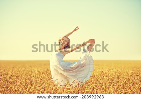 happy young woman enjoying life in golden wheat field