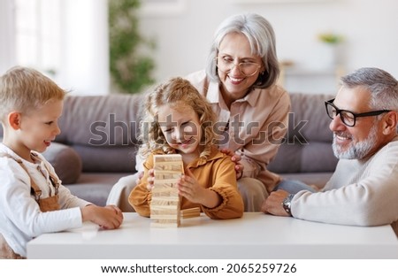 Similar – Image, Stock Photo Excited girl playing jenga game with her mom in play room. Girl removing one block from stack and placing it on top of tower. Game of skill and fun. Family time