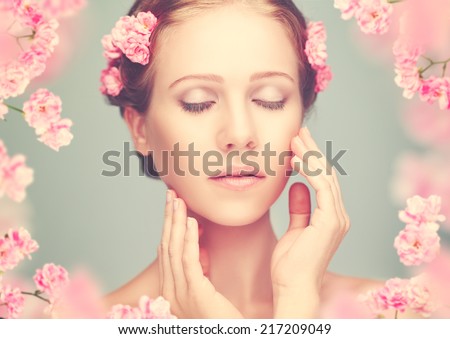 Beauty face of the young beautiful woman with pink flowers in her hair