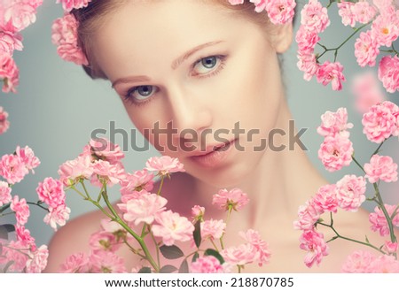Beauty face of the young beautiful woman with pink flowers in her hair