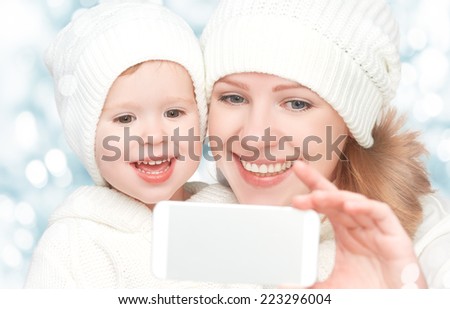 selfe  in winter. happy family mother with baby daughter and photographed self  on a mobile phone