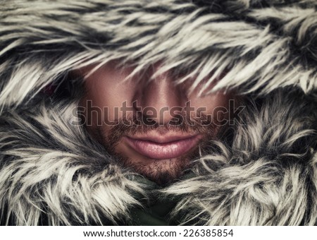 brutal face of a man with beard bristles and hooded winter