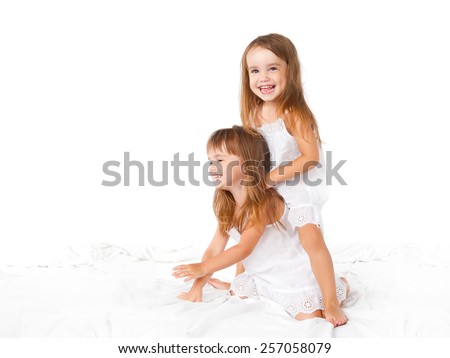 happy family at home. kids twin sisters jumping on the bed, playing and laughing
