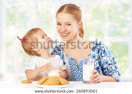happy family mother and baby daughter  child girl at breakfast: biscuits with milk