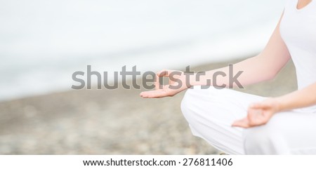 hand of a woman meditating in a yoga pose on the beach