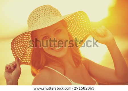 beauty happy smiling woman in a hat at sea at sunset on the beach