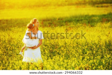 happy family, mother and little daughter girl child in the summer meadow with yellow flowers