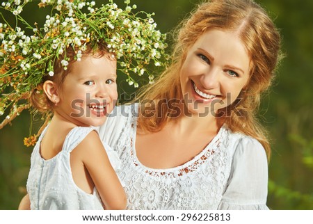 happy laughing family, daughter hugging mother in wreaths of summer flowers in nature