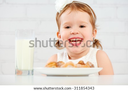 happy child little girl eats cookies and milk