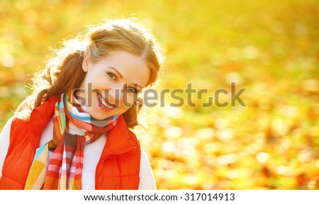 face of a happy girl with autumn leaves on a walk