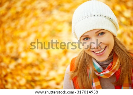 the face of a happy girl with autumn leaves on a walk