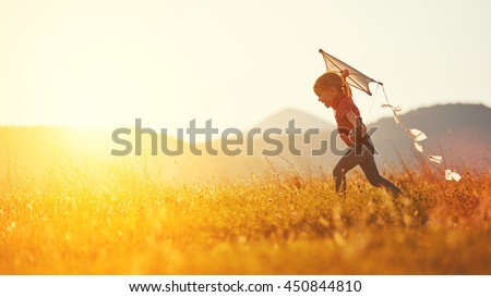 Photo of happy child girl with a kite running on meadow in summer in nature