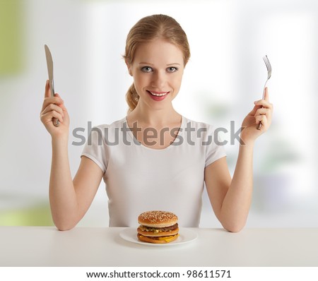 dinner time. pretty young woman with a knife and fork, and hamburger
