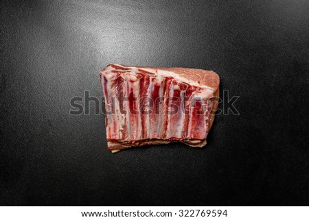 Raw pork ribs on black background. Fresh pork ribs or loin bone of pig. Piece of red raw meat on a black background