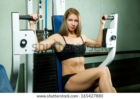 Beautiful sporty muscular woman at the old gym working out on a machine