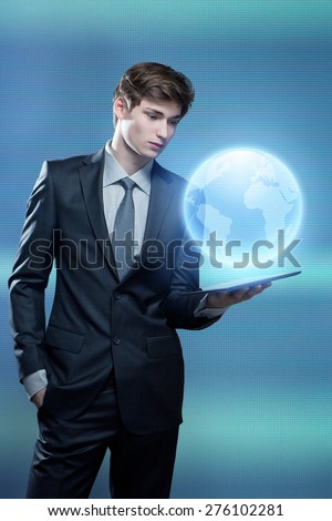 Portrait of young businessman with touch screen computer with hologram of the earth coming out of  computer