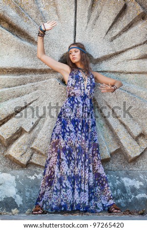 Young woman in a sundress at the stone wall
