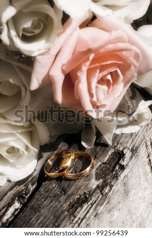 Wedding bunch of flowers and gold rings on old wood