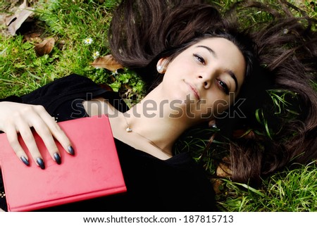 young girl relaxing over grass garden with a book in her hand