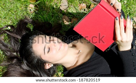 beautiful girl reading a funny book in outdoor scene