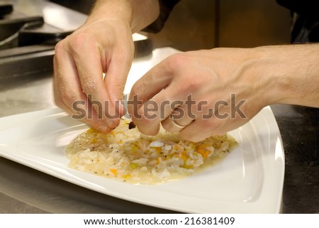 chef hands over fish risotto with pumpkin flowers