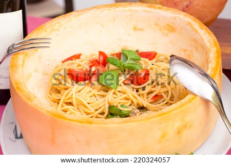 delicious recipe with spaghetti and saute cherry tomato, basil and eggplant inside cheese wheel
