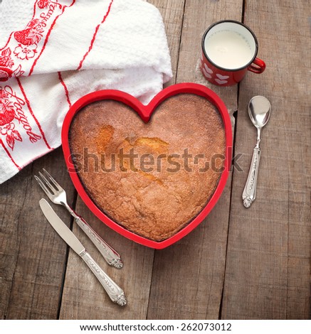 breakfast cake inside heart baking tin over wood with vintage silverware and milk mug