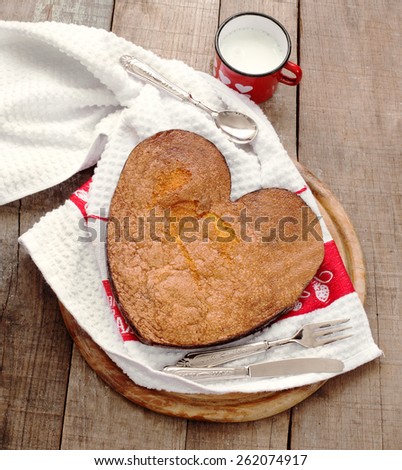 breakfast cake inside heart baking tin over wood with vintage silverware and milk mug