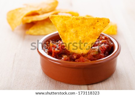 fried tortilla chip with a hot tomato salsa dip