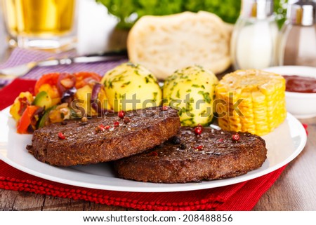 2 pieces of beefsteaks with fresh sliced corncob, potatoes and grilled veggies