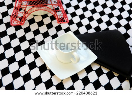 white square coffee cup on saucer with black napkin and red Eiffel tower decoration for dinner party